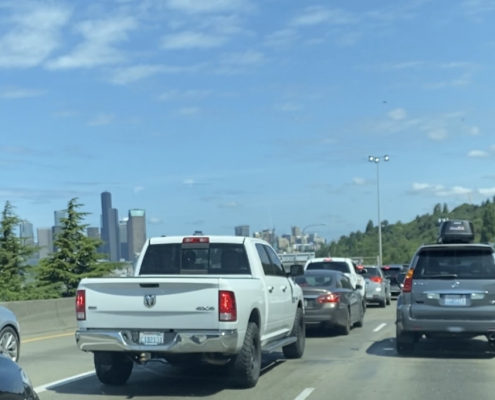 Traffic jam on city highway with pine trees and Seattle city skyline in the distance